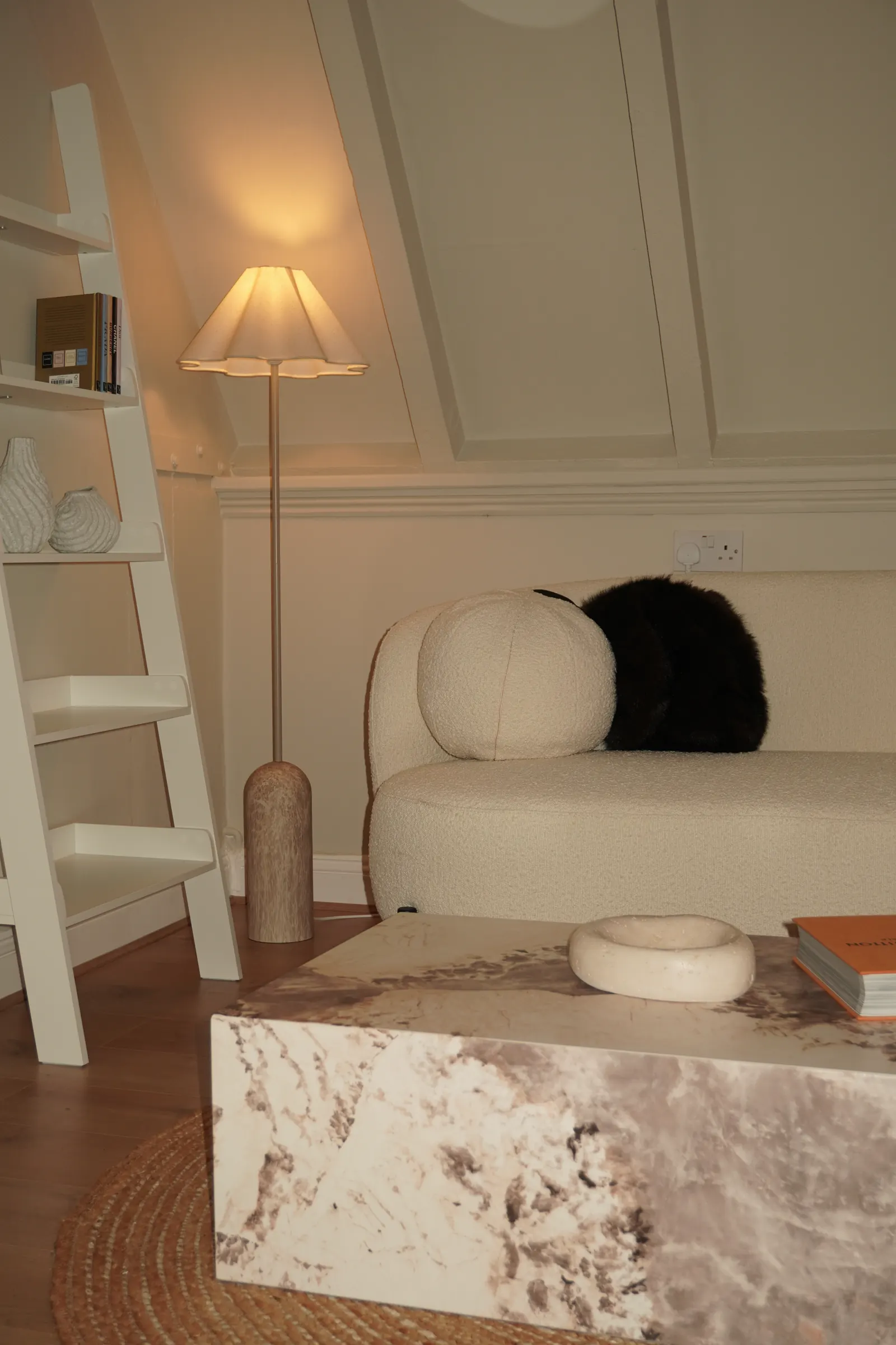 The lounge area with a boucle sofa, lamp and marble table