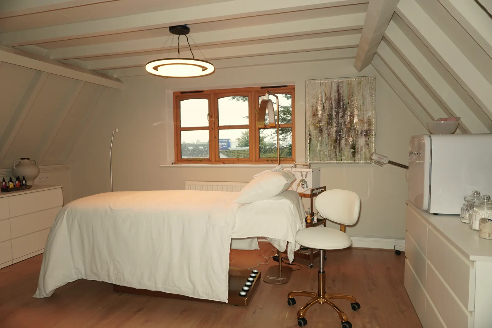 The treatment room with a made-up treatment bed beneath a window